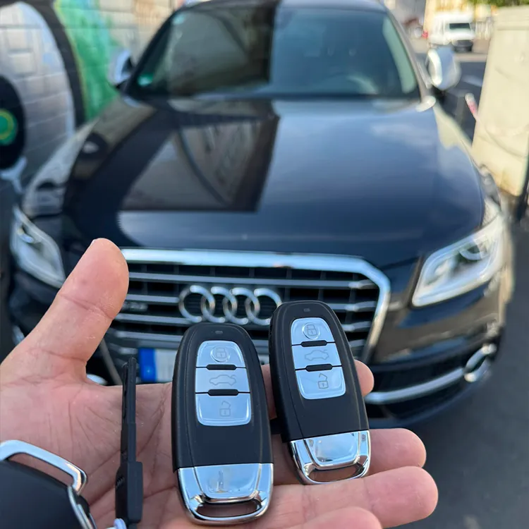 In der Hand 2 nachgemachte Audi Schlüssel, Auto im Hintergrund - Kundenauftrag