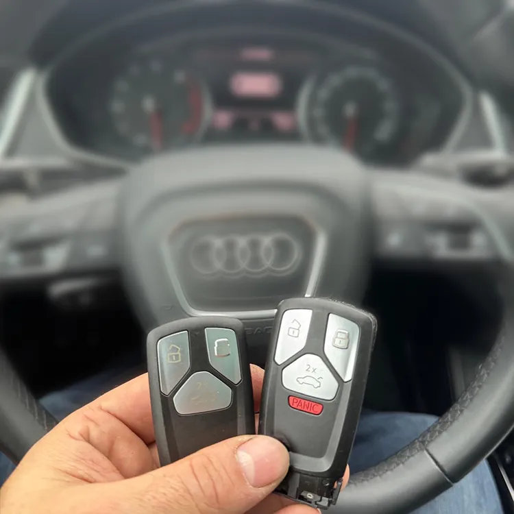 Von uns nachgemachte Audi-Schlüssel in der Hand, Lenkrad im Hintergrund - Kundenauftrag